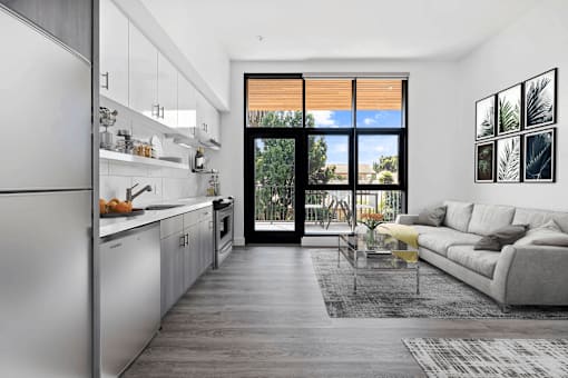 A modern kitchen with a refrigerator on the left and a living room with a couch and a coffee table on the right.