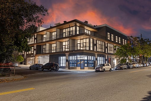 A building with a blue door and windows is surrounded by parked cars.