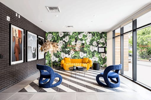 A room with a yellow sofa and blue chairs.