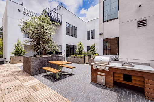 A patio with a table and chairs and a grill.