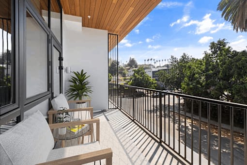 A balcony with a table and chairs overlooking a street.