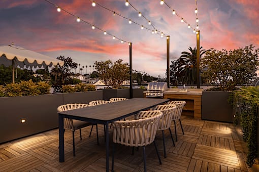 A table with chairs and lights on a terrace.