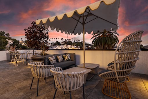 A patio with a table, chairs and an umbrella.