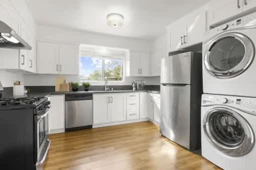 A modern kitchen with a washing machine and dryer built into the cabinetry.