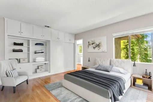 A bedroom with a bed, chair, and shelves.