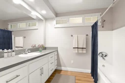 A bathroom with a sink, mirror, and shower.