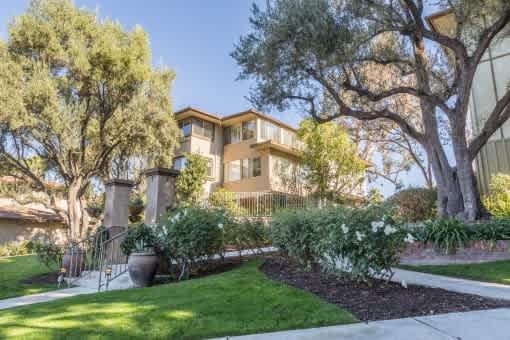 A house with a well-maintained lawn and trees in front.