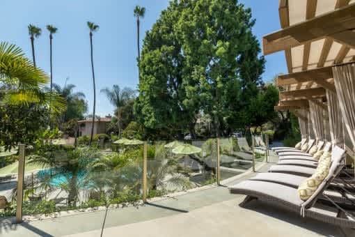 A pool surrounded by trees and lounge chairs.