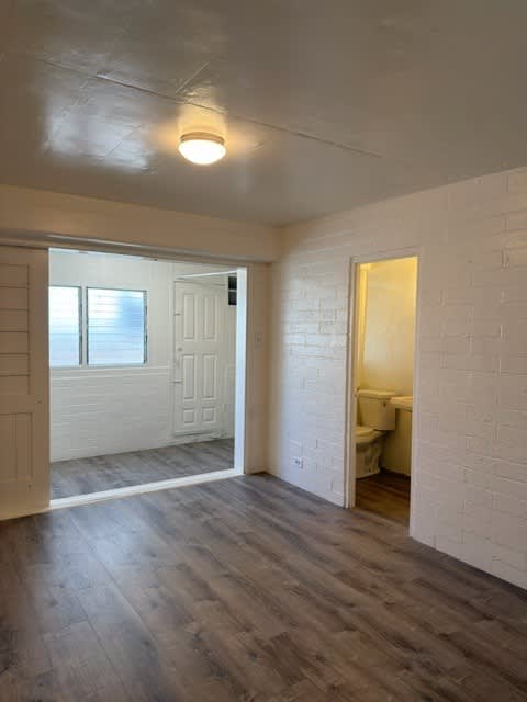 Pacific Oasis bedroom with a wooden floor and white walls.
