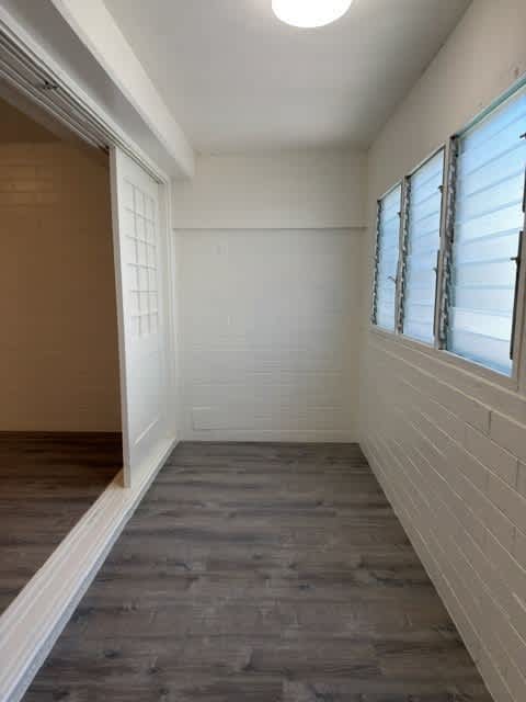 Pacific Oasis den with a wooden floor and white brick walls.