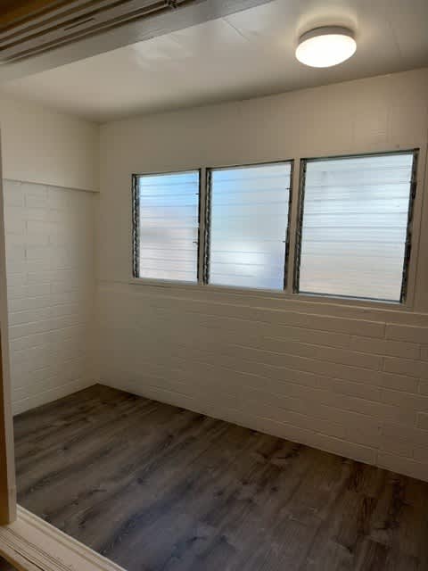 Pacific Oasis den with a window and a wooden floor.