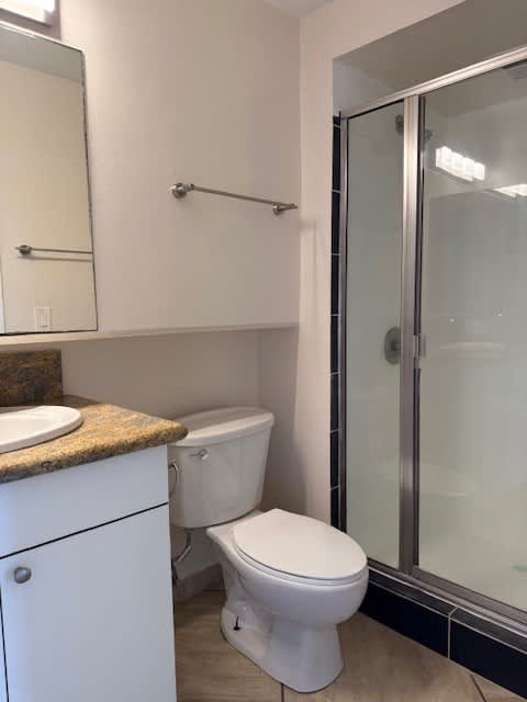 A white toilet sits in a bathroom next to a glass shower door.