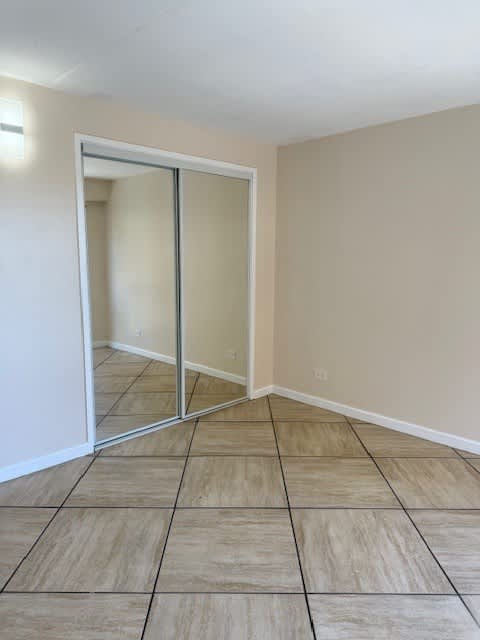 A room with a sliding glass door and tiled flooring.