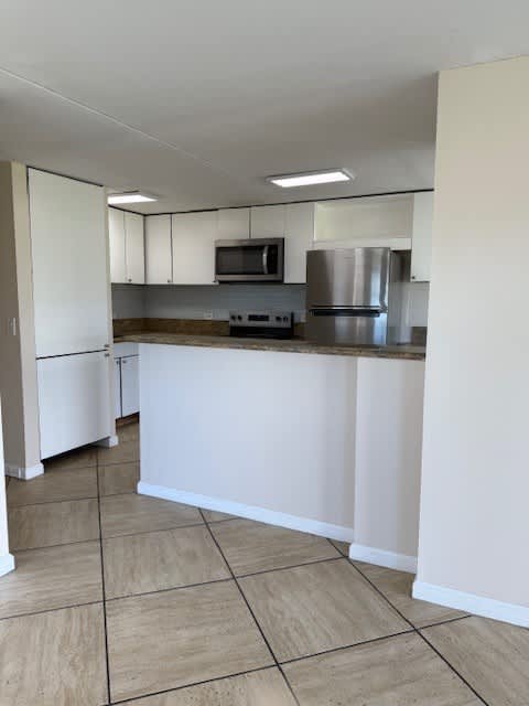 Napili Towers kitchen with white cabinets and a stainless steel refrigerator.