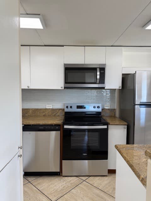 Napili Towers kitchen with a stove top oven and a microwave above it.