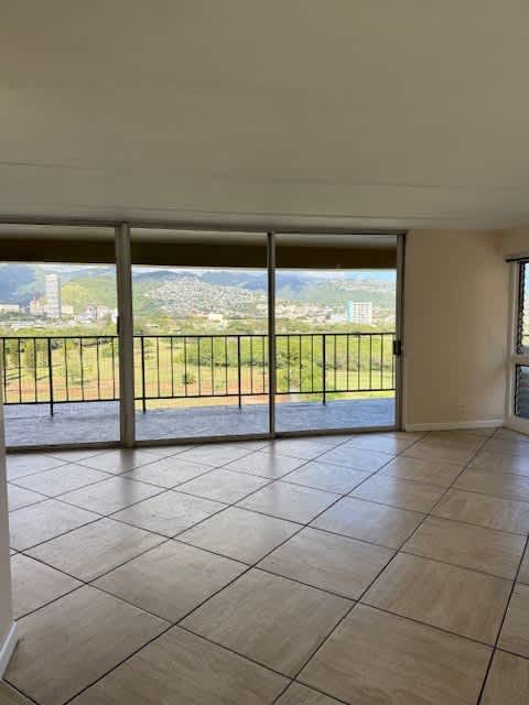 Napili Towers living room with a large tiled floor and a view of the city through the sliding glass doors.