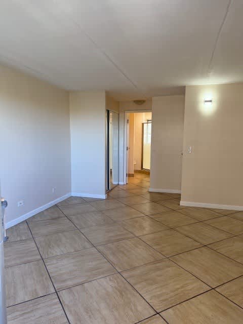 A long, empty hallway with tiled flooring and white walls.