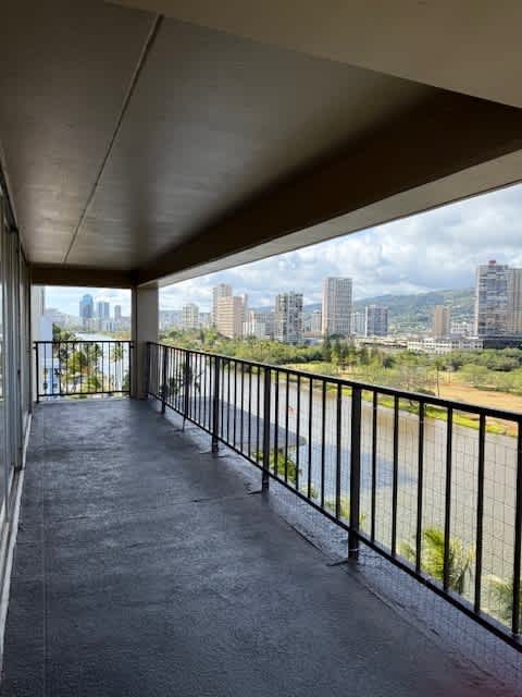 A balcony with a metal railing overlooks a cityscape.