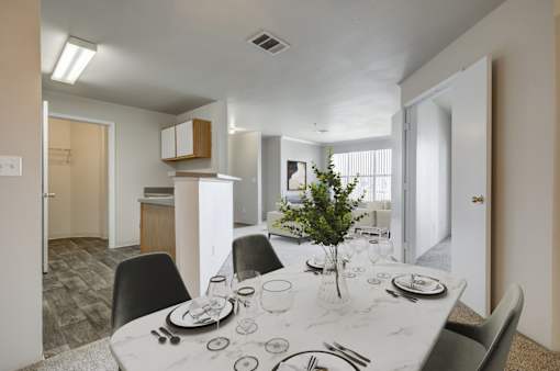 A dining room with a table set for two with a plant in the middle.