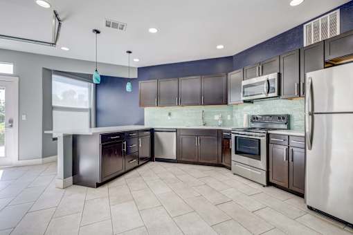 A kitchen with a white refrigerator, stainless steel oven, and black cabinets.