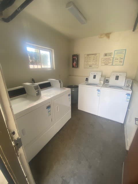 a laundry room with three washing machines and dryers