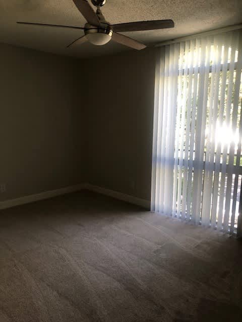 A room with a ceiling fan and carpeted floor.