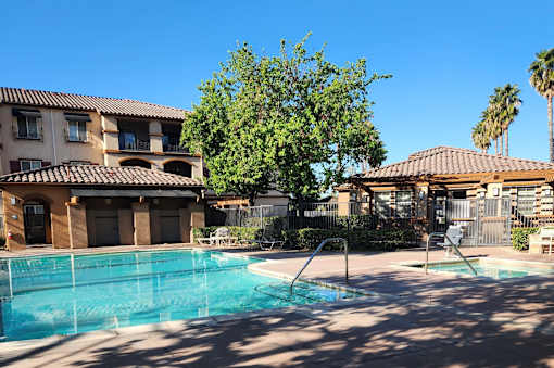 A swimming pool in front of a building with a tree in the background.
