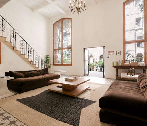 A living room with a brown couch and a chandelier.