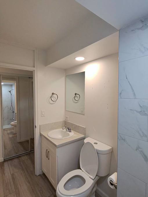 A white toilet with a sink and mirror in a bathroom.