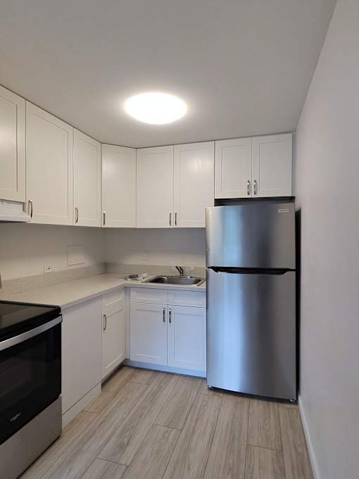 A kitchen with white cabinets and a stainless steel refrigerator.
