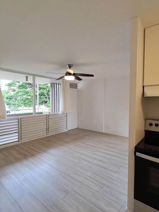 A room with a ceiling fan and a stove top oven.