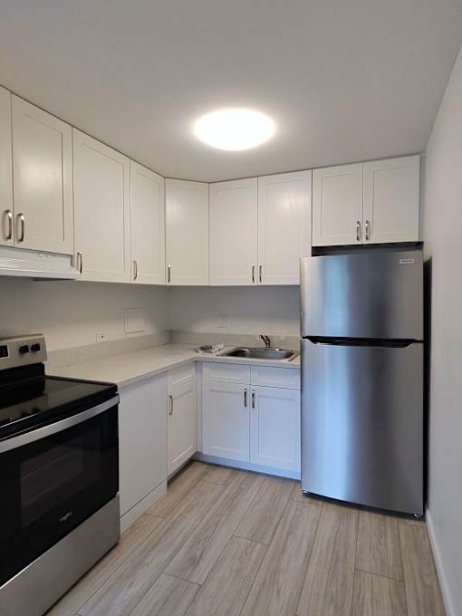 A kitchen with white cabinets and a stainless steel refrigerator.
