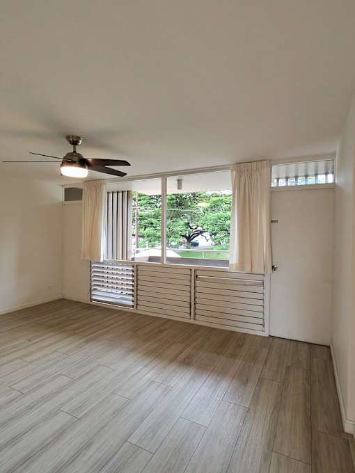 A room with a ceiling fan and a window with blinds.