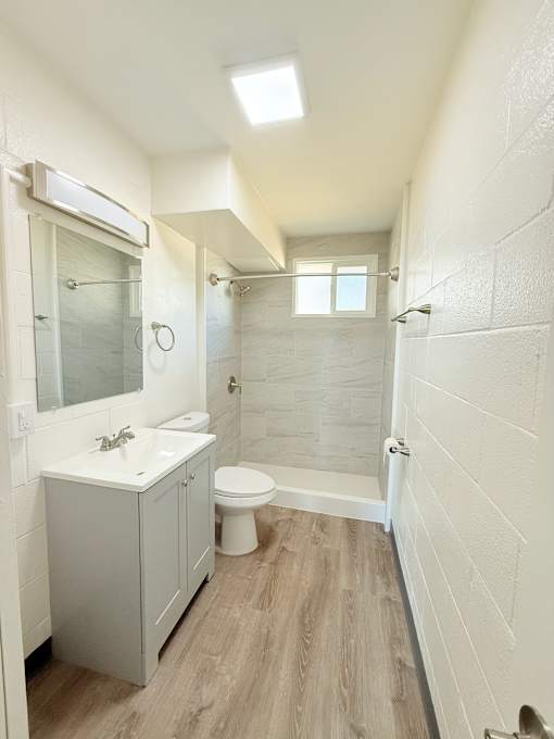 A white bathroom with a toilet, sink, and shower.
