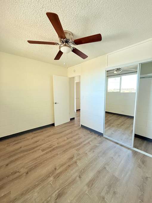A room with a ceiling fan and wooden flooring.