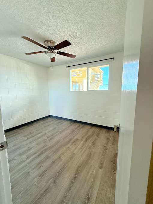 A room with a ceiling fan and a window with blinds.
