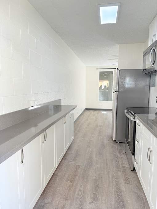 A kitchen with white cabinets and a black countertop.