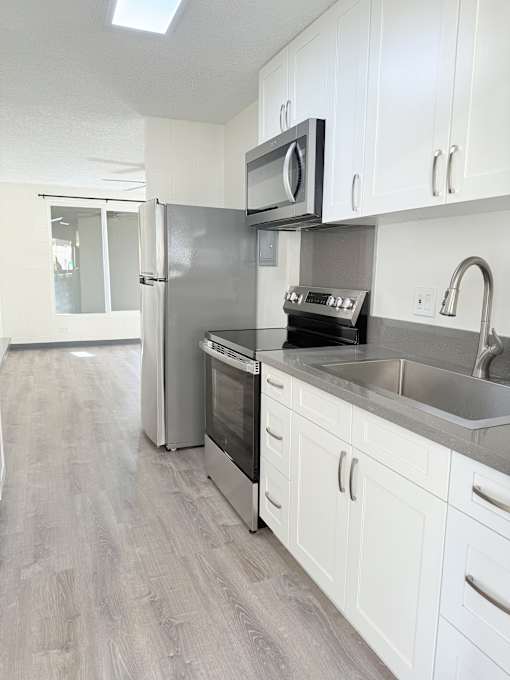 A kitchen with white cabinets and a black countertop.