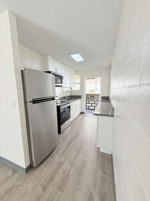 A kitchen with a refrigerator, oven, and cabinets.
