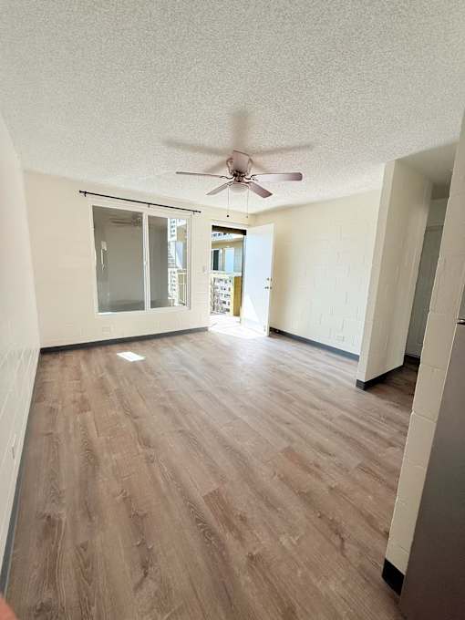 A room with a ceiling fan and wooden flooring.