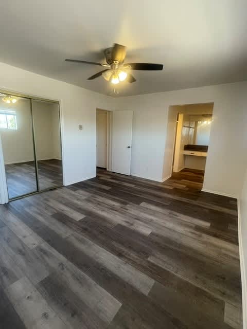 Seaview bedroom with a ceiling fan and wooden flooring.