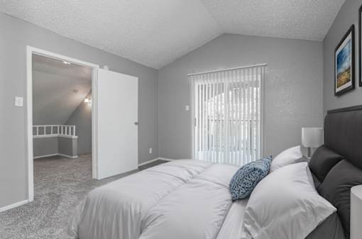 A bedroom with a bed, pillows, and a window with blinds.