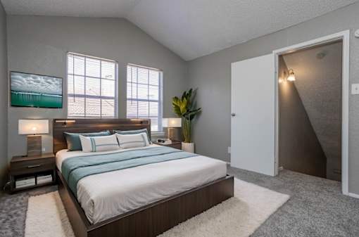 A bedroom with a large bed and a painting on the wall.