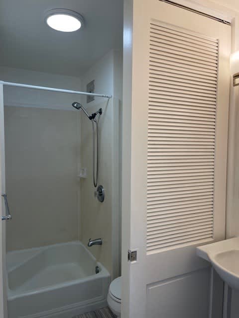 A white bathroom with a toilet, sink, and shower.