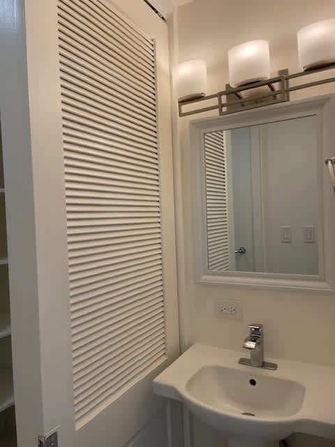 A white sink under a mirror with a light above it.