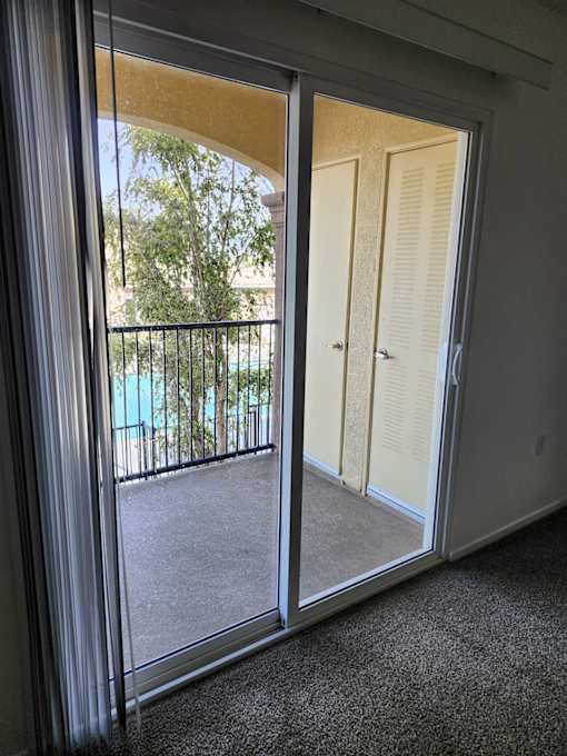 A room with a sliding glass door leading to a balcony.