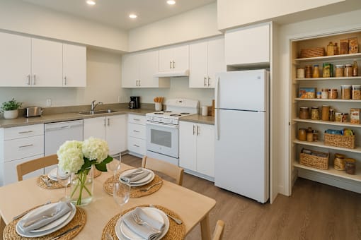 A kitchen with white cabinets and a white refrigerator with a pantry on the side.
