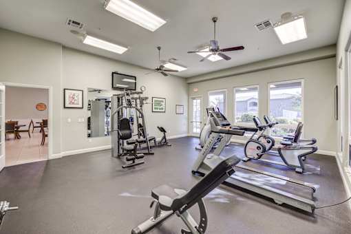 A spacious gym with treadmills, elliptical machines, and a weight machine.