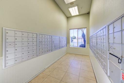 A room with a long row of mailboxes on both sides and a window in the middle.