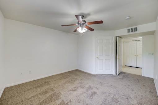 A room with a ceiling fan and carpeted floor.